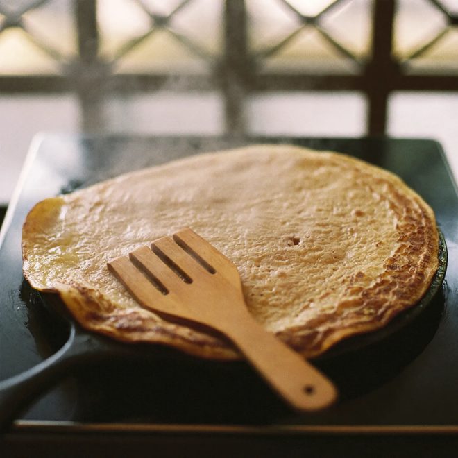 A crepe cooking on a cast iron hot plate