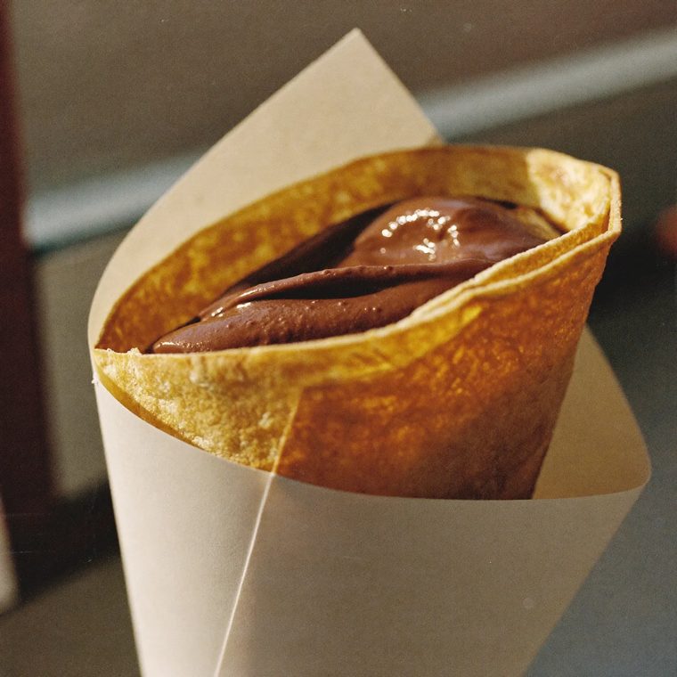 A crepe filled with chocolate spread, folded into a paper cone